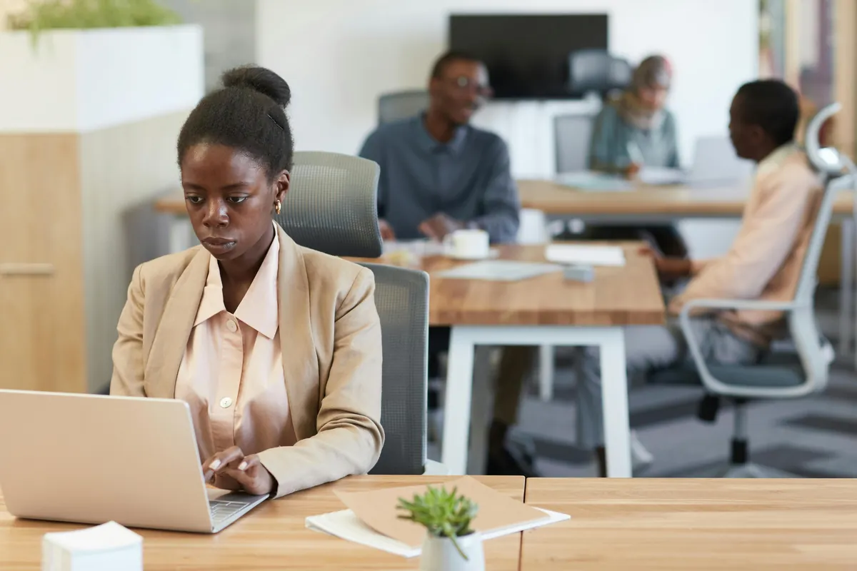 A woman working on a laptop in an open-plan office