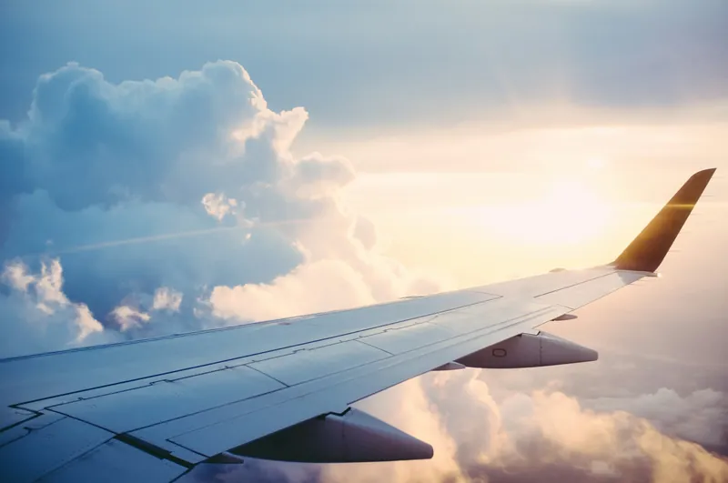 An aircraft wing above the clouds at sunset